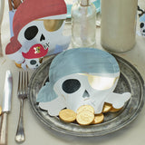 A pirate-themed table setting featuring a skull-shaped paper plate with gold foil chocolate coins.
