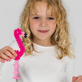 Young girl holding a pink flamingo made of Plus-Plus building blocks.
