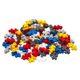 A colorful pile of red, blue, yellow, gray, and white Plus-Plus building blocks on a white background.