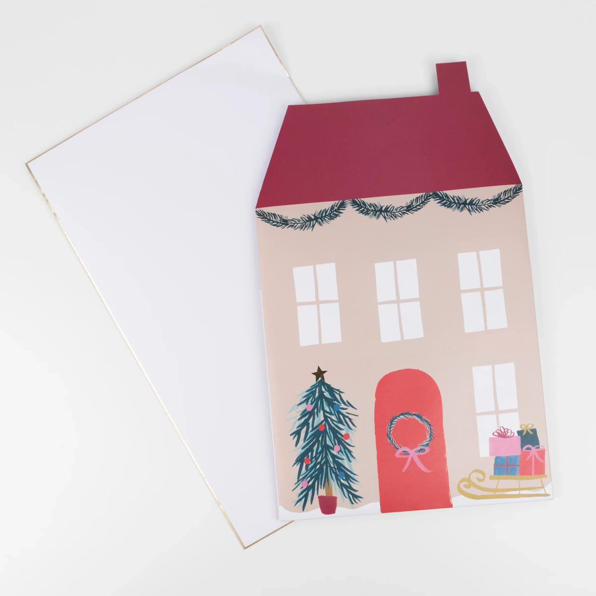 Flat Santa's house pop-up advent calendar lying next to its white envelope.