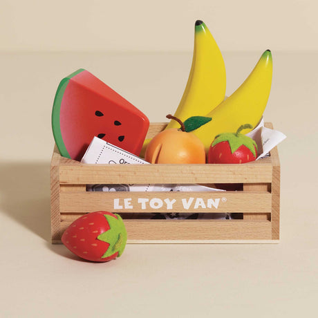 Wooden play fruit set in a Le Toy Van crate with a strawberry in front, on beige backdrop.