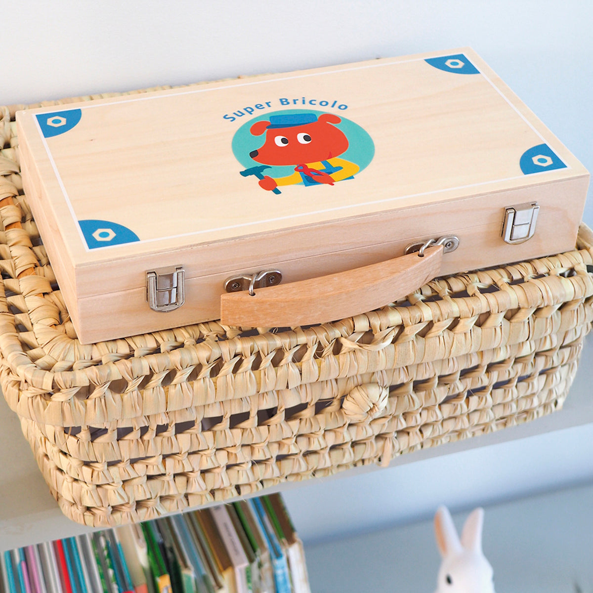 Super Bricolo wooden toy tool set case for children, resting on a woven wicker basket.