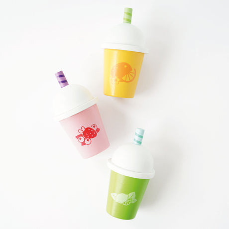 Flat lay view of three colorful wooden play smoothie cups with white domed lids and straws.