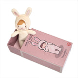 Small plush doll wearing a cream bunny suit sitting inside its open matchbox-style box.