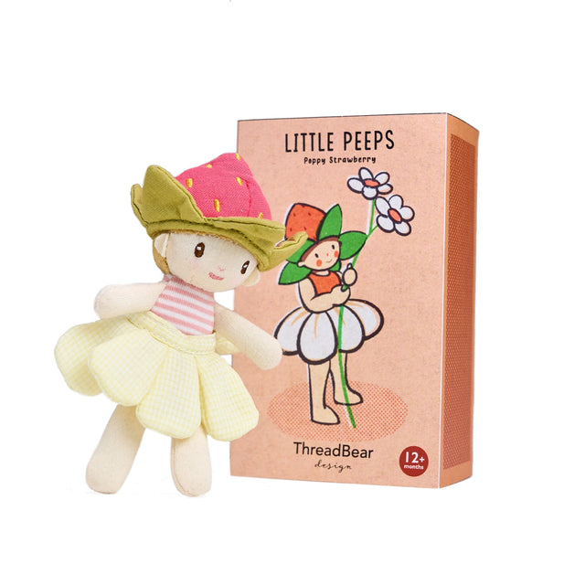 Small "Little Peeps Poppy Strawberry" plush doll wearing a strawberry hat and yellow skirt, standing next to its peach-colored illustrated box.
