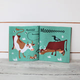 Open fabric book showing cows, mice, flies, and a bird on teal pages.