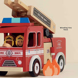 Red wooden toy fire engine with firefighters driving, winding fire hose, and fire cutouts.
