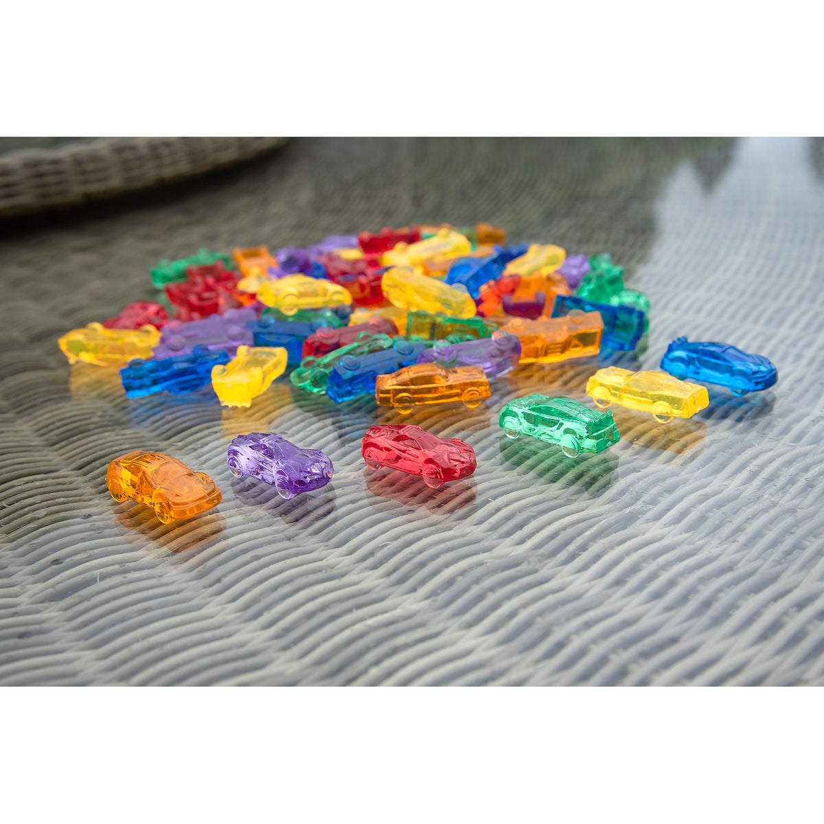 A set of small, see-through plastic cars in bright colors, designed to support imaginative play and color recognition in young children.