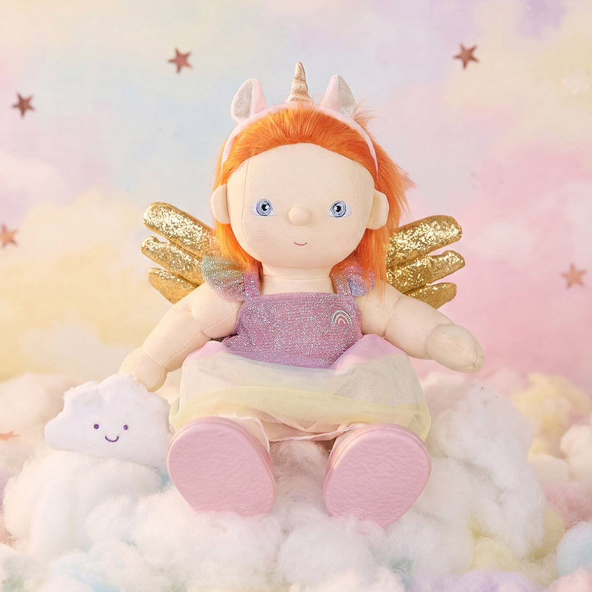 Olli Ella Dinkum Doll wearing a unicorn outfit set, sitting on clouds with a dreamy sky backdrop.