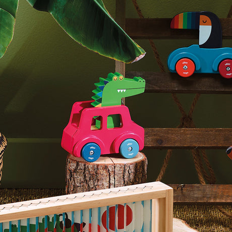 Vilac wooden crocodile toy car on a tree stump with a toucan toy vehicle in the background.
