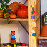 Vilac wooden lacing beads hanging on a shelf with pumpkins and a toy bear stacker in a cozy room.