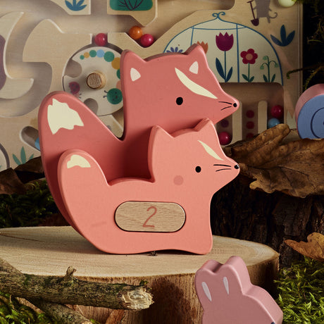 Vilac wooden fox stacking toy with the number 2 on a tree stump in a forest setting.