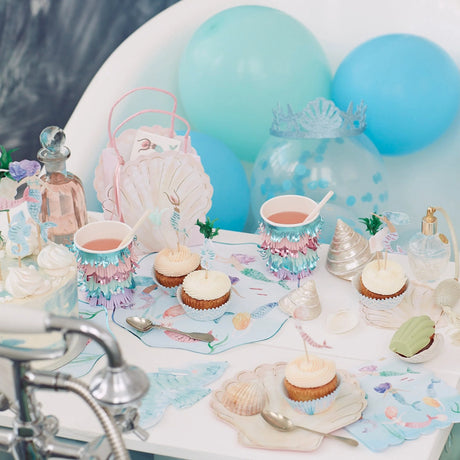 Mermaid-themed party table with cupcakes, decorated cups, balloons, and sea-themed party favors.