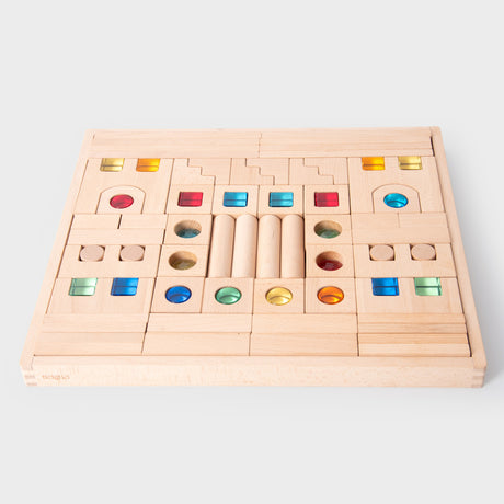 A large collection of wooden construction blocks with embedded colorful gems, designed to encourage creative building, light play, and sensory exploration.