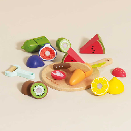 Wooden toy sliceable fruits and vegetables scattered around a chopping board on a beige surface.