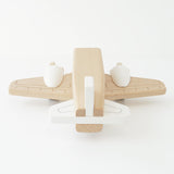 Minimalist natural wood and white toy airplane viewed from behind.
