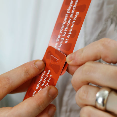 Hands connecting two red game cards together using a slot mechanism.