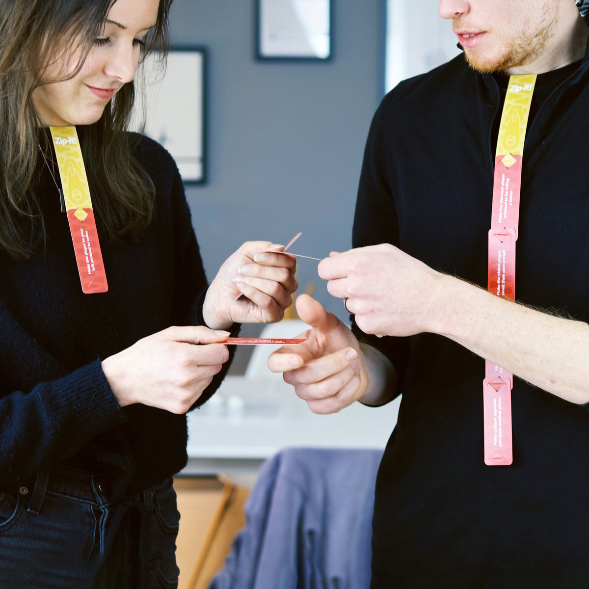Two people playing Zip-it!, wearing connected game cards hanging from their collars.